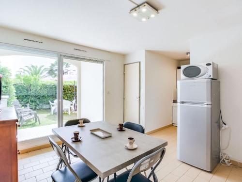 a kitchen and dining room with a table and a refrigerator at Apartment Les Frégates by Interhome in Saint-Cyprien-Plage