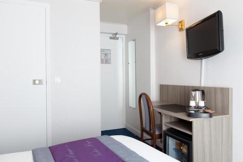 a hotel room with a bed and a desk with a tv at Saphir Grenelle in Paris