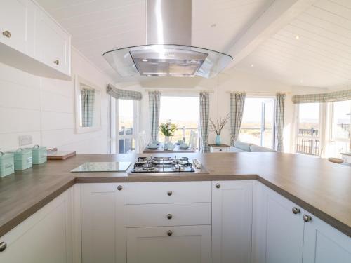 a kitchen with white cabinets and a stove top oven at Beech Lodge in Newton Abbot