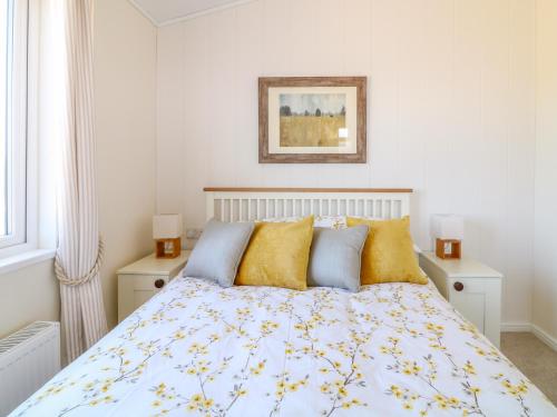 a white bedroom with a bed with yellow pillows at Beech Lodge in Newton Abbot
