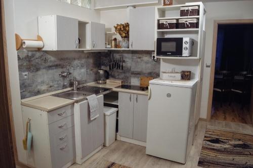 a kitchen with white cabinets and a sink and a microwave at Privát Vavrúš in Donovaly