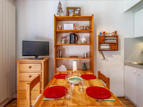 a dining room table with red plates and a television at Studio La Borgia A- B- C-11 by Interhome in Les Contamines-Montjoie