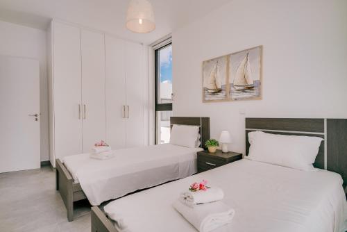 two beds in a room with white walls and windows at SunnyVillas: 2BR New Villa☆Private Pool in Pernera - Nicholas in Protaras