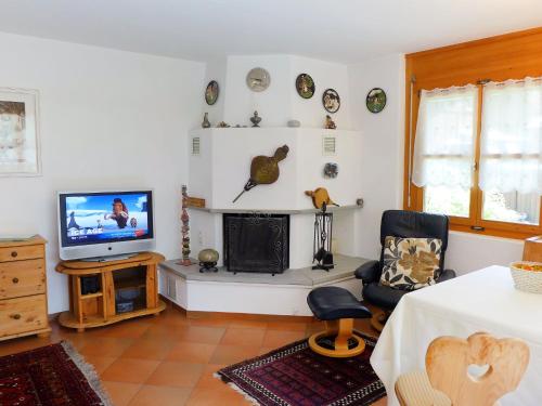 ein Wohnzimmer mit einem Kamin und einem TV in der Unterkunft Apartment Casa La Planüra by Interhome in Maloja