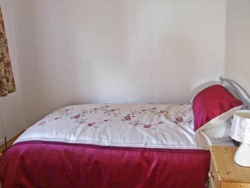 a bedroom with a bed with a red and white comforter at The Stables in Edale