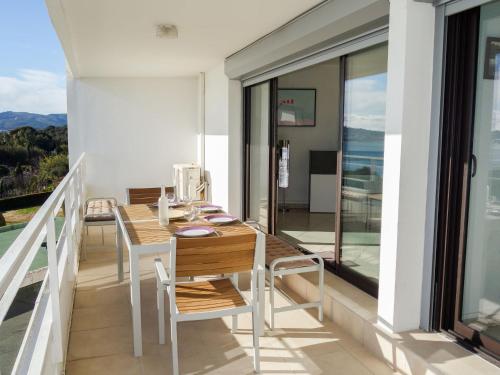 een balkon met een houten tafel en stoelen erop bij Apartment Les Hauts de Fonsainte by Interhome in La Ciotat