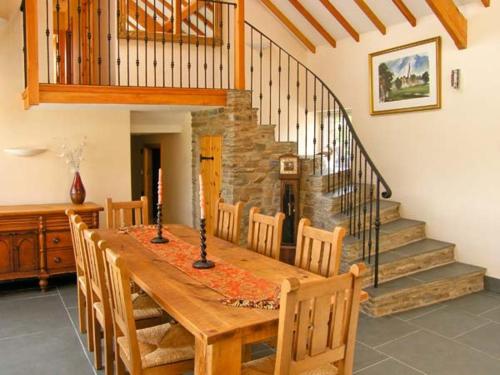 a dining room with a wooden table and a staircase at Garth Morthin The Barn in Morfa Bychan