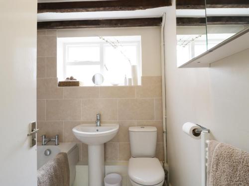ein Badezimmer mit Toilette und Waschbecken und einem Fenster in der Unterkunft Causeway Cottage in Pencombe