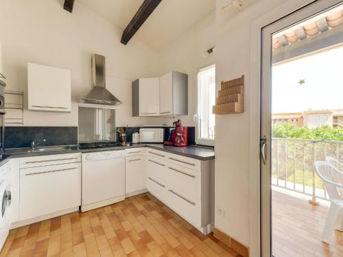 une cuisine avec des placards blancs et une grande fenêtre dans l'établissement Apartment Les Maldives-3 by Interhome, au Cap d'Agde