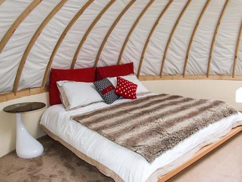 a bed with red and white pillows in a room at Secret Island Yurt in Beckford