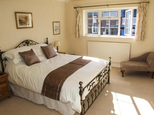 a bedroom with a bed and a chair and a window at Harris House in Ludlow