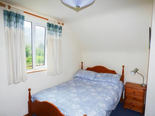 a bedroom with a bed and a window at Colbha Cottage in Portsalon