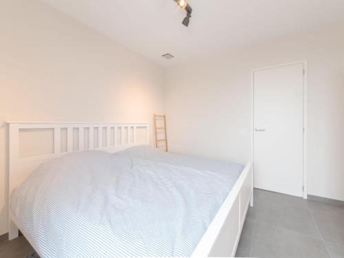 ein weißes Schlafzimmer mit einem Bett und einem Schrank in der Unterkunft Apartment Lakeside by Interhome in Bredene