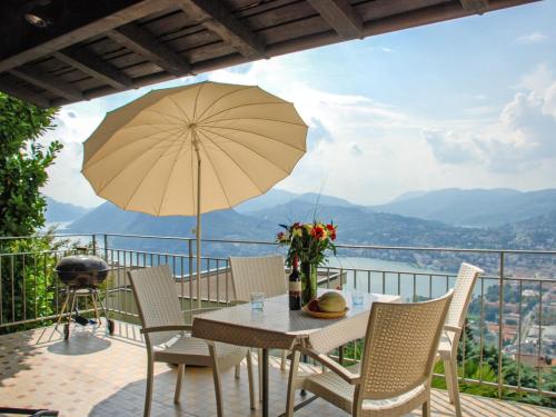 a table and chairs with an umbrella on a balcony at Holiday Home Nido di Rondine-1 by Interhome in Viganello