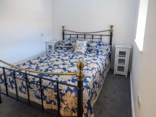 a bedroom with a bed with a blue and white comforter at 3 Primitive Croft in Chelmorton