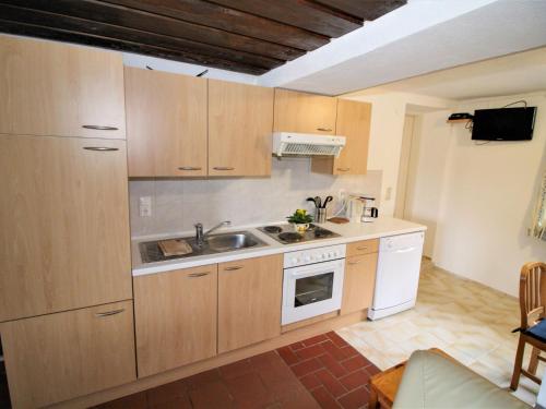 a kitchen with wooden cabinets and a sink at Apartment Fuchsbau-Top 2 by Interhome in Grünau im Almtal