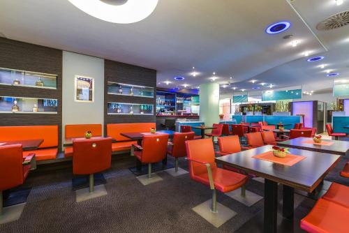 a restaurant with tables and orange chairs at Novina Hotel Wöhrdersee Nürnberg City in Nürnberg