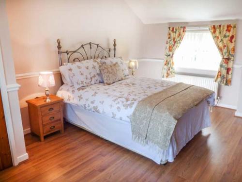 a bedroom with a bed and a nightstand and a window at Arfryn in Bethesda