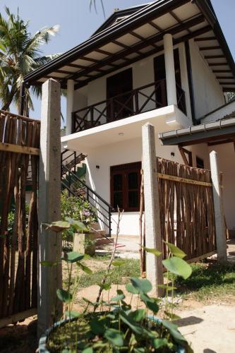 a house with a wooden fence in front of it at Surf Nest Hiriketiya in Dickwella