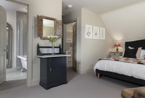 a bedroom with a bed and a sink and a mirror at The Hideaway in Moreton in Marsh