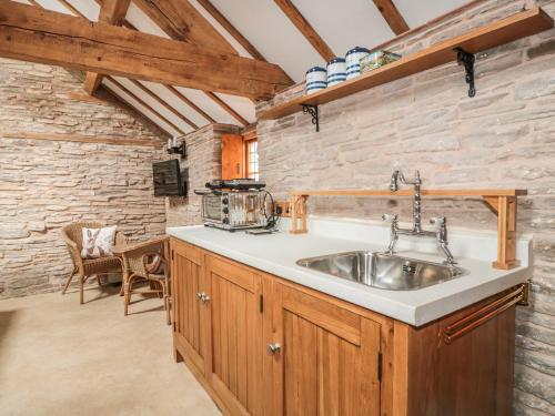 a kitchen with a sink and a stone wall at The Cow Cott in Peterchurch