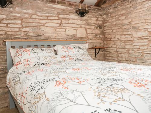 a bed in a room with a stone wall at The Cow Cott in Peterchurch