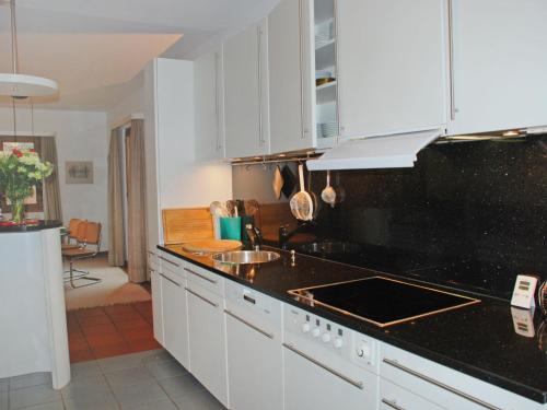 una cucina con armadi bianchi e piano di lavoro nero di Holiday Home Riva by Interhome a Figino