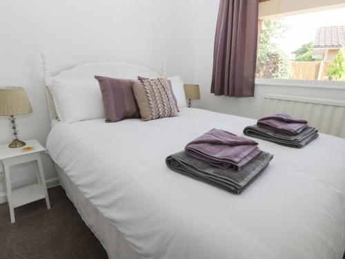 Alberts Lodge في Boultham: غرفة نوم بسرير ابيض عليها مناشف