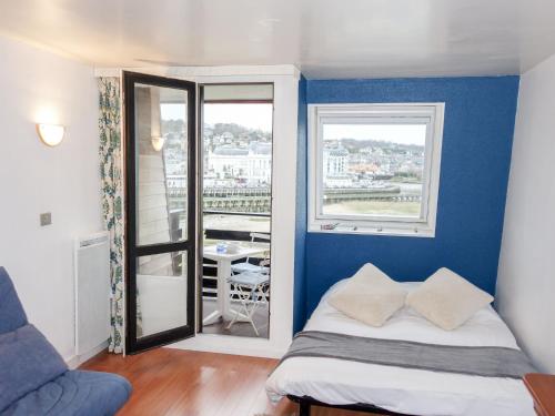 a bedroom with a blue wall with a bed and a window at Studio Les Marinas-10 by Interhome in Deauville