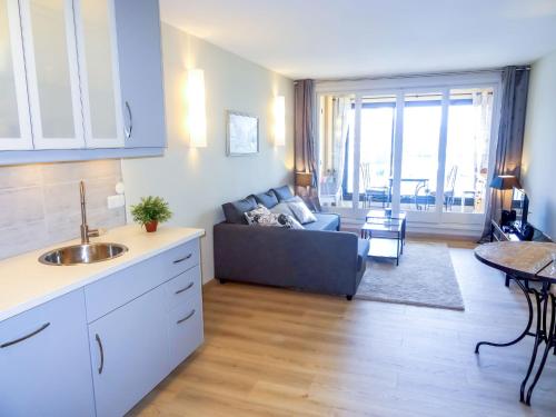 Apartment Les Cascadelles-10 by Interhome في La Foux: مطبخ وغرفة معيشة مع أريكة وطاولة