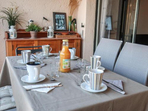 Apartment Les Cascadelles-10 by Interhome في La Foux: طاولة مع قماش الطاولة البيضاء وزجاجة من الصلصة