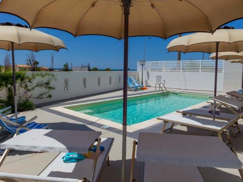 a pool with chairs and umbrellas next to a swimming pool at Apartment Talìa Luna by Interhome in Sampieri