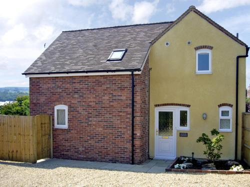 a small brick house with a white door at Manor Cottage in Ludlow