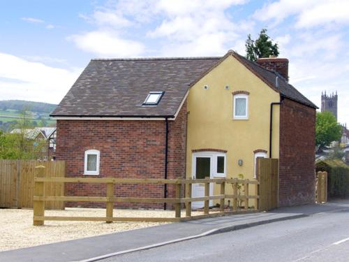 a yellow house with a wooden fence in front of it at Manor Cottage in Ludlow