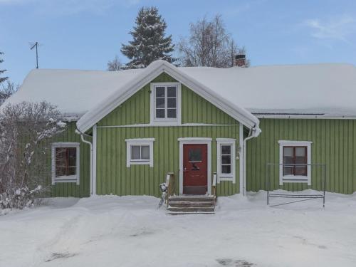 a green house with a red door in the snow at Holiday Home Palokärki by Interhome in Urimolahti