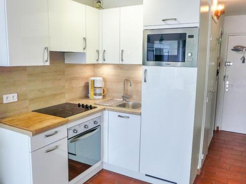 La cuisine blanche est équipée d'un évier et d'un réfrigérateur. dans l'établissement Apartment Les Jardins de la Plage-11 by Interhome, à Canet