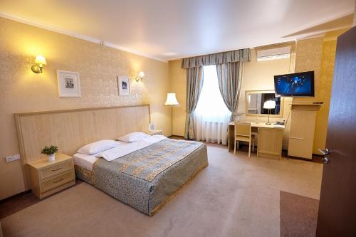 チマシェフスクにあるHotel Tetaのベッドとデスクが備わるホテルルームです。