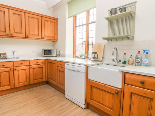 a kitchen with wooden cabinets and a white dishwasher at Hoath House in Chiddingstone