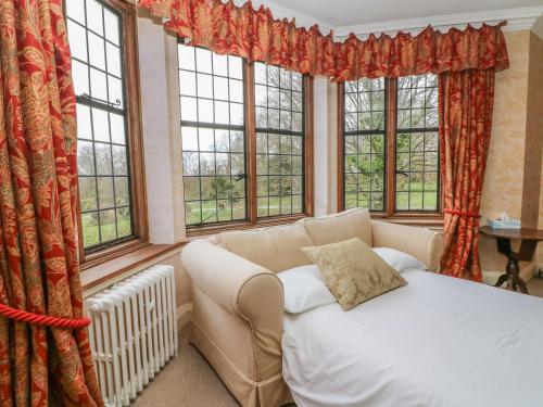 a living room with a couch and windows at Hoath House in Chiddingstone