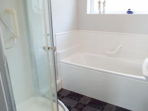 a white bathroom with a tub and a toilet at Lamora in Cheddar