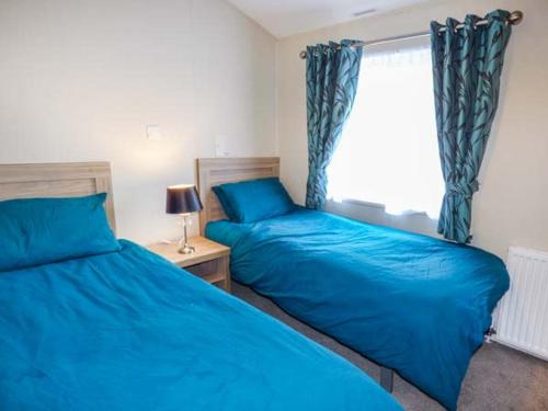 ボースにあるClearview Lodgeのベッドルーム(青いシーツ、窓付)のベッド2台