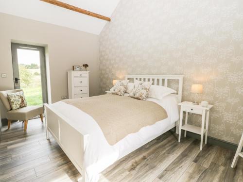 ein Schlafzimmer mit einem großen weißen Bett und einem Stuhl in der Unterkunft Lowdale Barns East in Sleights