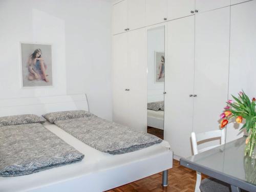 a white bedroom with two beds and a table at Apartment Apt- Lugano Majestic Panorama by Interhome in Lugano