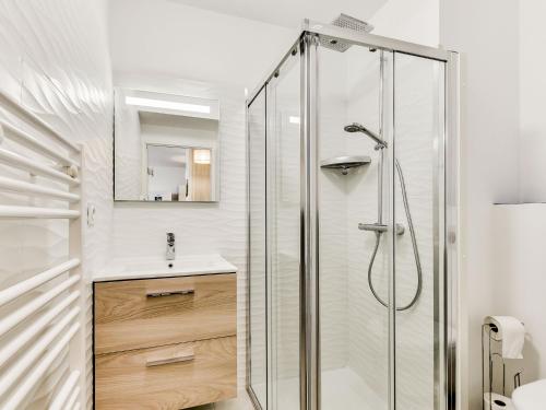 une salle de bain blanche avec une douche et un lavabo dans l'établissement Apartment Balnéa-2 by Interhome, à Sainte-Marie-Plage