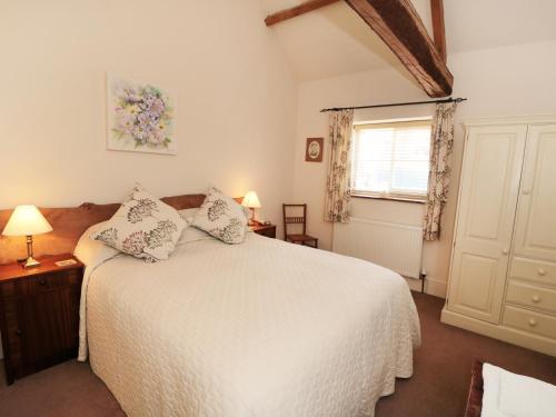 a bedroom with a white bed and a window at Henhouse Cottage in Gillamoor