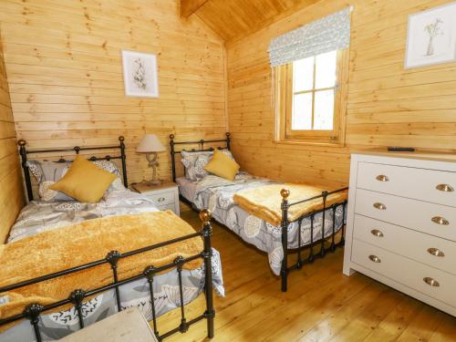 サックスマンダムにあるAcorn Lodgeの木造キャビン内のベッドルーム1室(ベッド2台付)