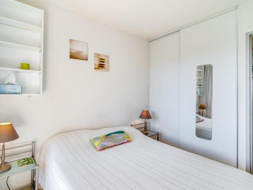 a white bedroom with a bed and a mirror at Apartment Les Quais de L'Amirauté-7 by Interhome in Saint Cyprien Plage