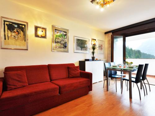 - un salon avec un canapé rouge et une table dans l'établissement Apartment Enrosadira-6 by Interhome, à Alba di Canazei