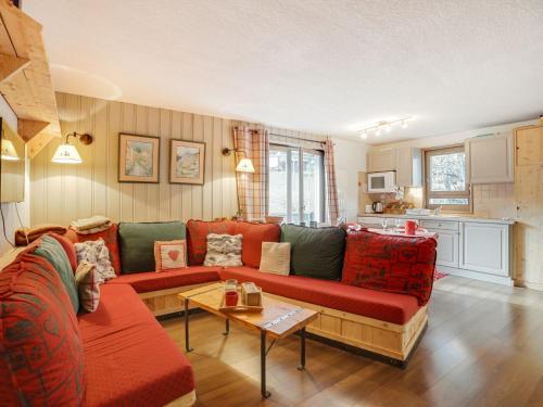 a living room with a red couch and a kitchen at Apartment Parc du Mont Joly-2 by Interhome in Saint-Gervais-les-Bains