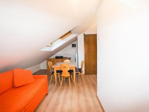 uma sala de estar com um sofá laranja e uma mesa em Apartment Enrosadira-7 by Interhome em Alba di Canazei